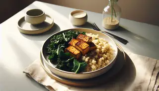 Vegan lunch with caramelized tofu on quinoa, crispy kale on a white plate, natural light, minimalist table setting.