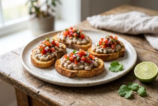 Swahili Coast Coconut Mbaazi Crostini Toasted bread topped with creamy coconut pigeon peas and fresh tomato kachumbari on a rustic plate.