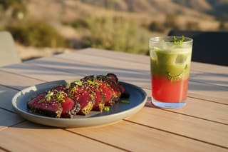 Smoked watermelon brisket with matcha-yuzu glaze and a layered matcha cooler on a sunlit California table. Vibrant vegan fusion BBQ.