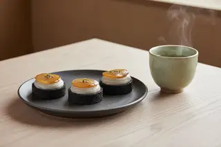 Vegan black sesame tartlets with Earl Grey cream and miso-pear, served with sencha tea in a minimalist Japanese Wabi-sabi setting.