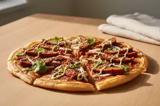 Vegan Gochujang BBQ seitan flatbread on a flaky scallion pancake, with wasabi mayo and cilantro, shot in warm, golden California sunlight.