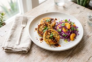 Crispy Masa-Crusted Mushroom Scallops with Ojai Citrus Slaw Crispy masa-crusted mushroom rounds served with a vibrant purple cabbage and citrus slaw on a white plate over a wooden table.