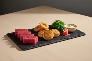 Minimalist vegan seafood: ruby watermelon sashimi, seared mushroom scallops, and hearts of palm on dark slate. Elegant Japanese plant-based art.