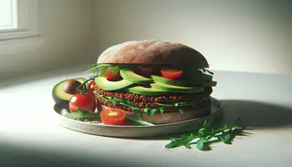 Open-faced vegan minced gourmet sandwich on a whole-grain bun with avocado, cherry tomatoes, and arugula, in a bright, minimalist setting.