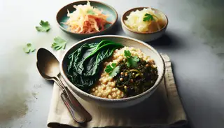 Minimalist African vegan lunch setting with sorghum porridge, sautéed collard greens garnished with coriander, and sauerkraut.