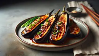 Broiled Miso-Glazed Eggplant on a ceramic plate, topped with sesame seeds and green onions, showcasing caramelized miso glaze.