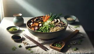 A vegan Asian breakfast bowl on a simple table, featuring quinoa, sautéed shiitake, tofu, carrots, edamame, spring onions, and sesame seeds, with soy sauce and chopsticks.