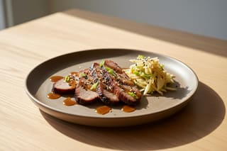 Smoked seitan brisket with maple-miso glaze and kimchi-apple slaw on stoneware, showcasing a vibrant vegan Asian-American BBQ fusion.