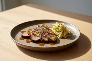 Smoked seitan brisket with maple-miso glaze and kimchi-apple slaw on stoneware, showcasing a vibrant vegan Asian-American BBQ fusion.