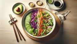 Vegan Asian fusion salad in a white bowl on a light wood table, with avocado slices, cilantro, and chopsticks.