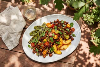 Vibrant guajillo tempeh crumble with charred nopales and peaches on a white platter, set on a sunlit redwood table in a California garden.