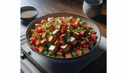 Image of an Asian-inspired American BBQ side dish featuring smoked tofu, red bell pepper, and green onions, sprinkled with sesame seeds, served in a stylish bowl on a bamboo background.