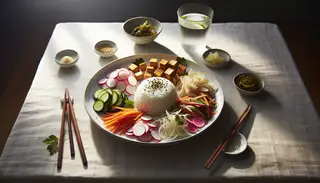 Image of a minimalist Asian-inspired vegan feast on a dining table featuring a white ceramic plate with jasmine rice, colorful pickled vegetables, golden-brown tofu, garnished with green onions, sesame seeds, and cilantro. Wooden chopsticks and a glass of water accompany the meal, all under natural light.