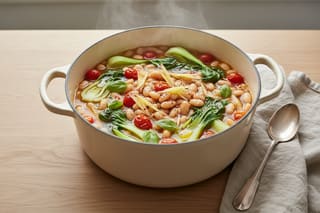 Vibrant Miso-Ginger Acqua Pazza with beans and bok choy in a ceramic pot. A steamy, plant-based fusion of Mediterranean and Asian umami flavors.