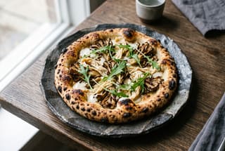 Shojin Harvest Pizza with Binchotan Maitake and Shiro Miso Cream Artisan vegan pizza with charred crust, grilled mushrooms, and miso cream on a dark ceramic plate.