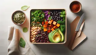 Minimalist table with an African-inspired vegan bento box, containing sorghum, seasoned sweet potatoes, kale, cabbage, black beans, avocado, pumpkin seeds, raisins, and cilantro.