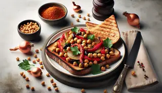 African-inspired vegan lunch: whole grain bread with pan-roasted chickpeas, red bell pepper, onions, and parsley on a clean table setting.