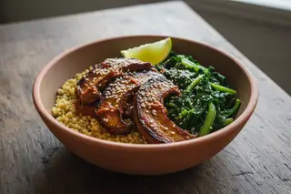 Vegan Mshikaki bowl: Glazed King Oyster mushrooms, golden millet, and Sukuma Wiki in a terracotta dish. Minimalist, elegant food photography.