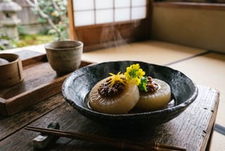 Binchotan-Charred Daikon with Toasted Walnut Miso Simmered daikon rounds topped with rich walnut miso in a dark ceramic bowl, garnished with a yellow flower on a rustic wooden table.